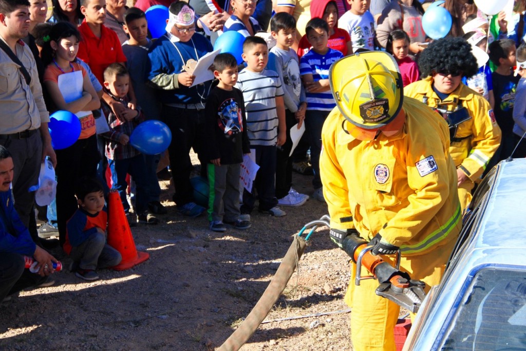 Children at a home safety and fire prevention fair in Nogales, Mexico, watch firefighters extricate a supposed victim from a damaged vehicle. Photo by Ieva Jusionyte.